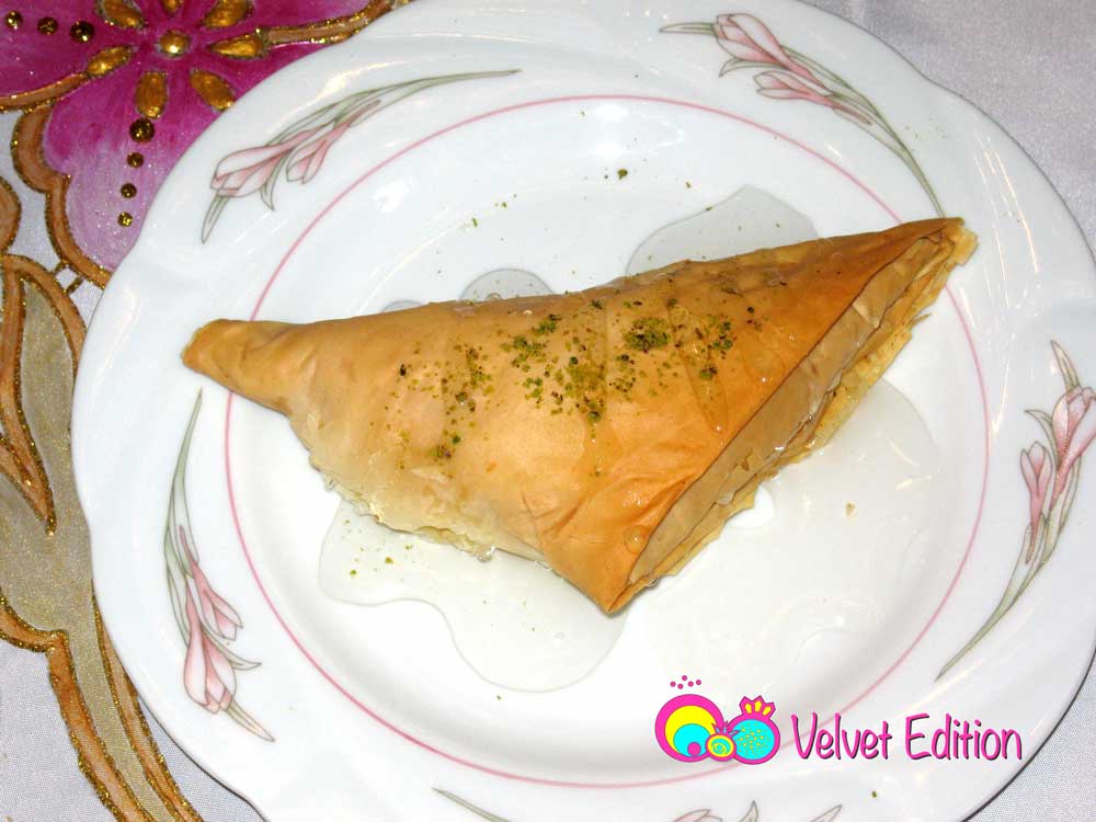 Shaabiyat served warm with syrup and ground pistachios.