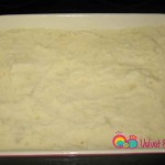 Empty half the mashed potatoes over the bottom of the baking pan.