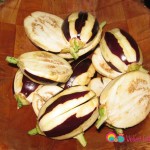 Remove the leaves around the tip, peel the skin giving it a striped look and cut the eggplants in half.